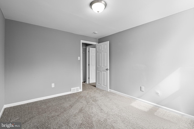 empty room featuring visible vents, carpet floors, and baseboards