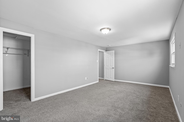 unfurnished bedroom with a walk in closet, carpet floors, baseboards, and a closet