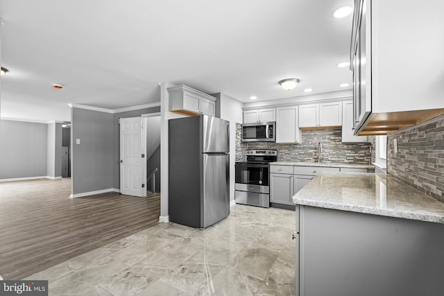 kitchen featuring light stone counters, tasteful backsplash, appliances with stainless steel finishes, and a sink