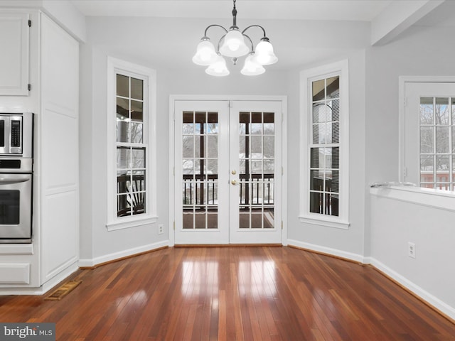 unfurnished dining area featuring french doors, baseboards, dark wood-style flooring, and an inviting chandelier