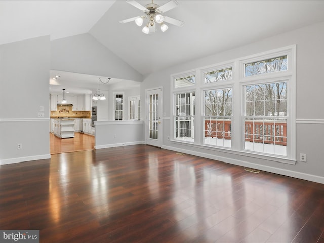 unfurnished living room with ceiling fan with notable chandelier, dark wood-style flooring, visible vents, and baseboards