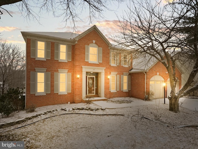 colonial home with brick siding, driveway, and an attached garage