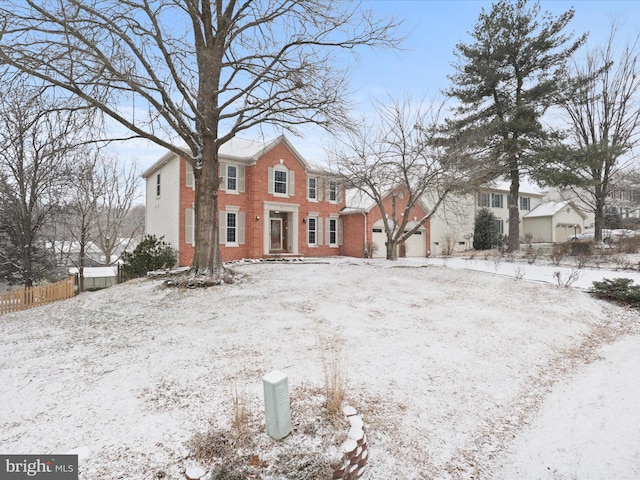 view of front of home with an attached garage, fence, and brick siding