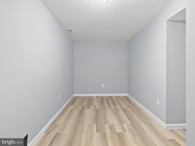 empty room featuring light wood-type flooring, visible vents, and baseboards