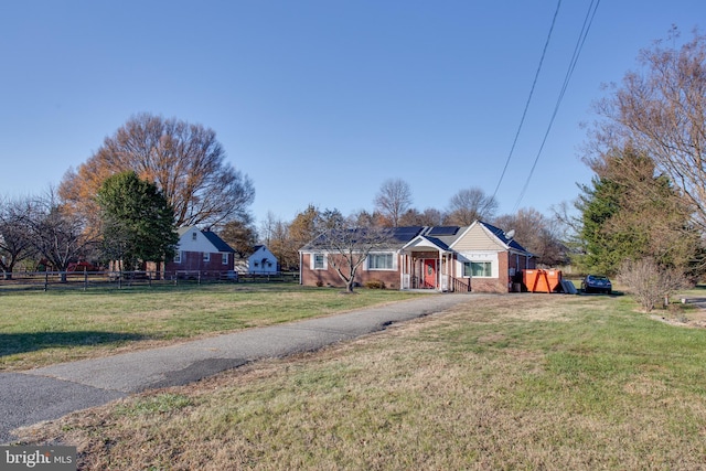 view of front of home featuring driveway, brick siding, fence, and a front yard