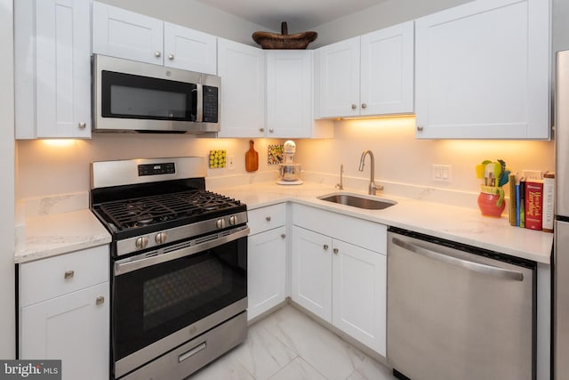 kitchen with marble finish floor, stainless steel appliances, a sink, and white cabinets