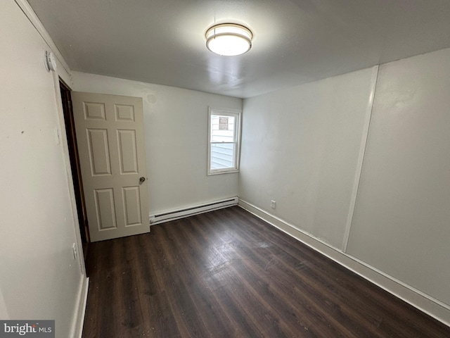 unfurnished room with a baseboard heating unit, dark wood finished floors, and baseboards