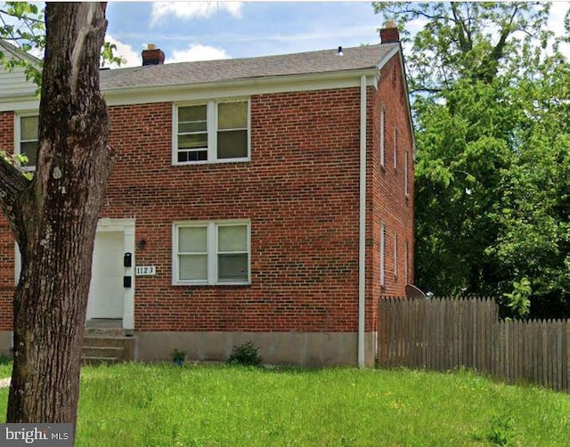 view of front of house featuring entry steps, brick siding, a chimney, and fence