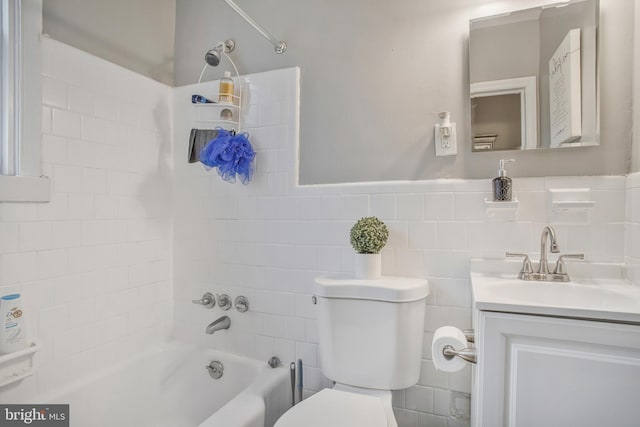 bathroom with shower / bathtub combination, vanity, toilet, and tile walls