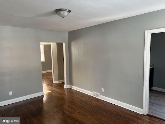 empty room featuring wood finished floors, visible vents, and baseboards