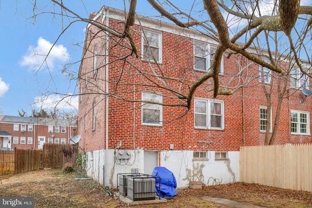 view of home's exterior featuring fence, central AC, and brick siding