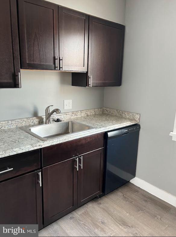 kitchen with dishwasher, light countertops, dark brown cabinets, light wood-style floors, and a sink