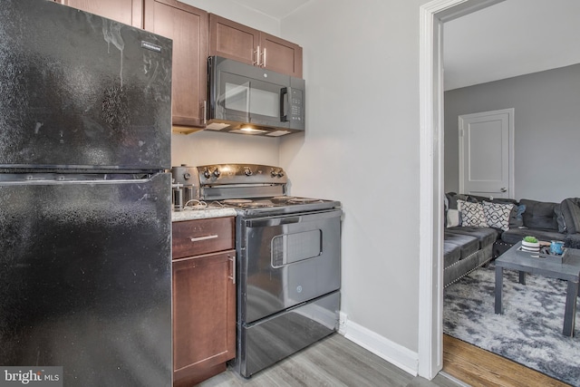 kitchen with light wood-type flooring, black appliances, and baseboards