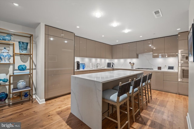 kitchen featuring a center island, light wood-style floors, gray cabinets, decorative backsplash, and modern cabinets