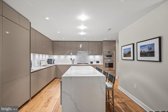 kitchen with stainless steel double oven, gray cabinets, gas stovetop, and modern cabinets