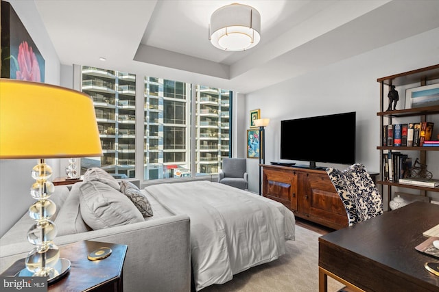 bedroom featuring a tray ceiling and a wall of windows