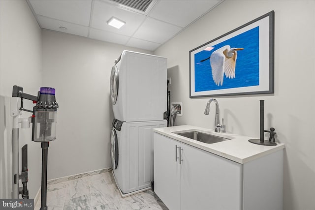 laundry room featuring cabinet space, stacked washer and dryer, visible vents, marble finish floor, and a sink