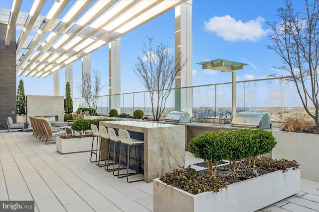 view of patio with area for grilling, a pergola, an outdoor kitchen, and an outdoor fireplace