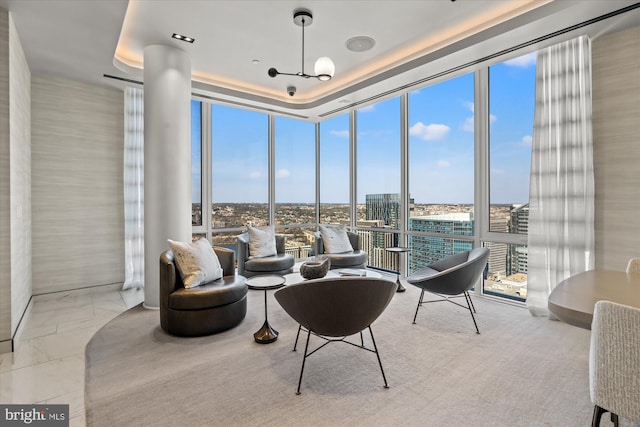 interior space featuring an inviting chandelier, expansive windows, a raised ceiling, and a city view