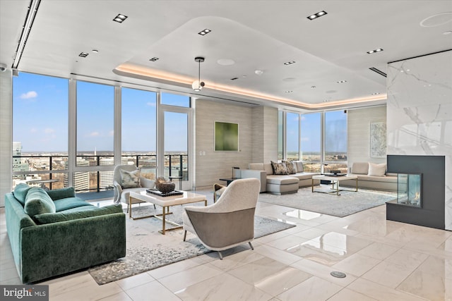 living room featuring a wall of windows, a raised ceiling, and a premium fireplace