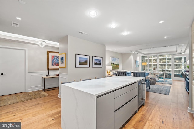 kitchen with light wood-style floors, wainscoting, visible vents, and a center island