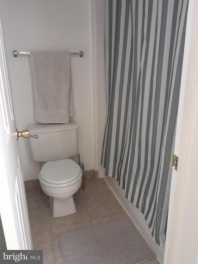 full bathroom featuring toilet, curtained shower, and tile patterned floors