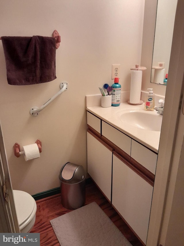 half bath featuring toilet, wood finished floors, and vanity