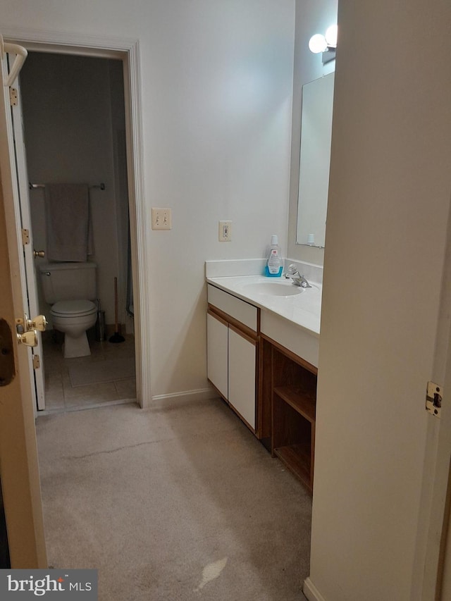 bathroom with baseboards, vanity, and toilet