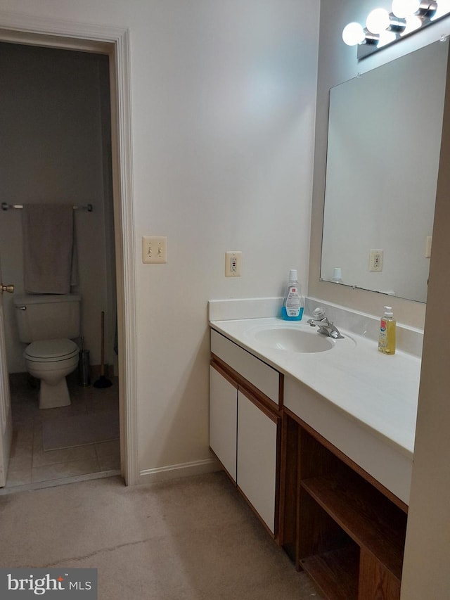 bathroom featuring toilet, vanity, and baseboards