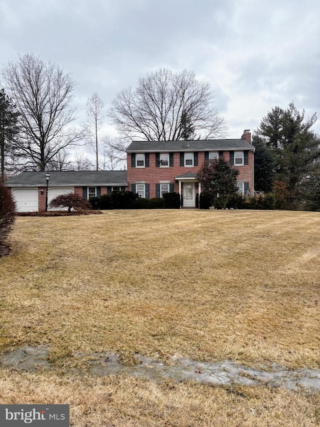 view of front facade with a chimney, a front lawn, and brick siding