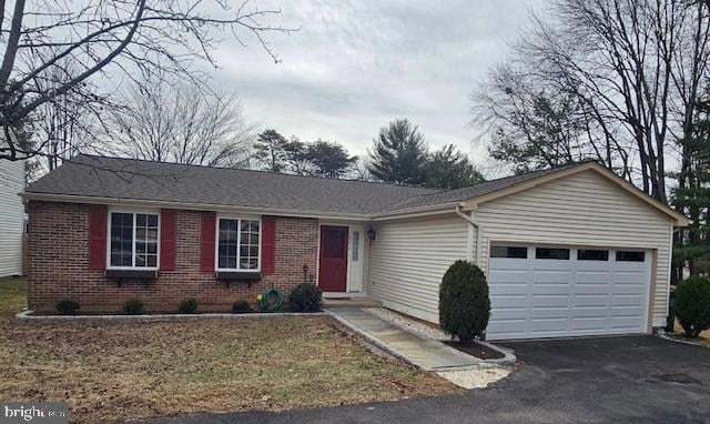 single story home featuring aphalt driveway, an attached garage, and brick siding