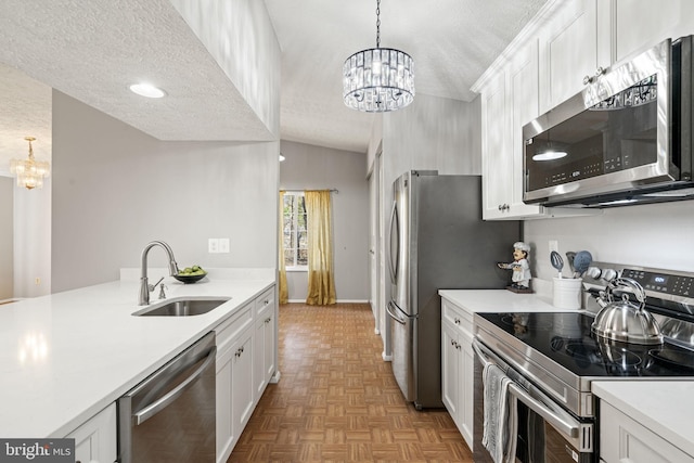 kitchen featuring a sink, a textured ceiling, stainless steel appliances, an inviting chandelier, and light countertops