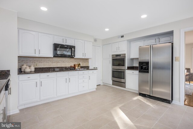 kitchen featuring visible vents, black appliances, decorative backsplash, and dark stone counters