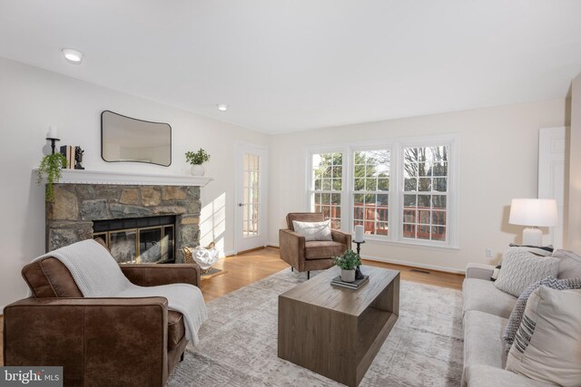 living room featuring light wood finished floors, visible vents, a fireplace, and baseboards