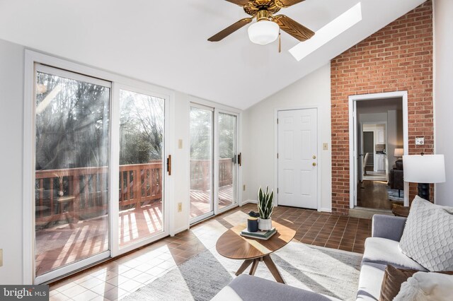 tiled living area featuring vaulted ceiling with skylight and a ceiling fan