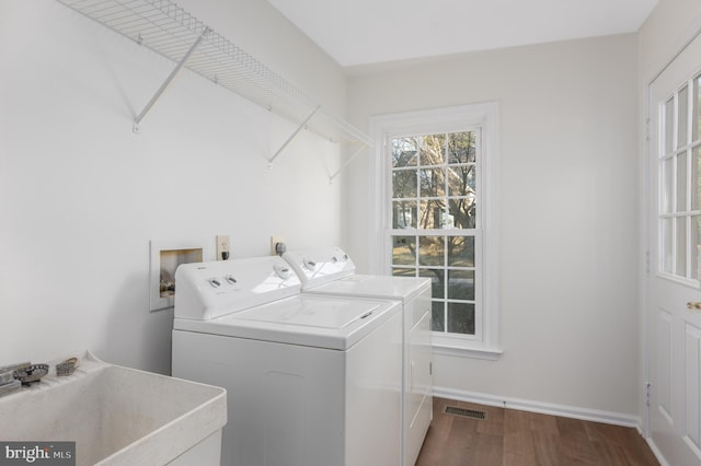 washroom with washing machine and clothes dryer, visible vents, a sink, laundry area, and dark wood-style flooring