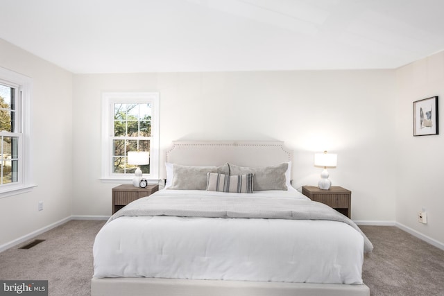 carpeted bedroom featuring visible vents, multiple windows, and baseboards