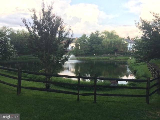 view of home's community featuring a yard, a water view, and fence