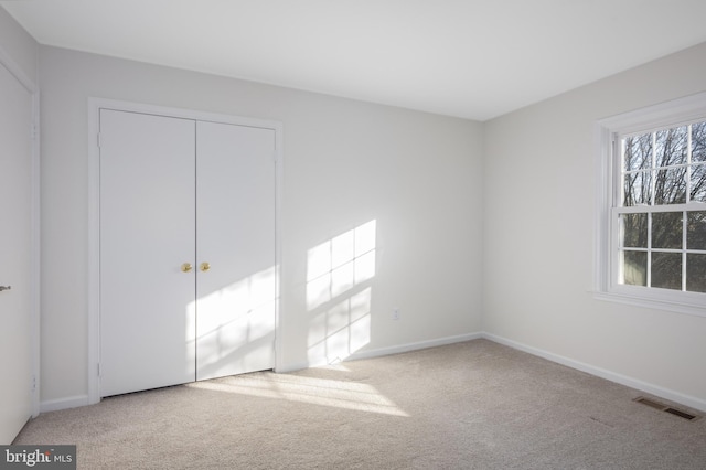 unfurnished bedroom featuring a closet, baseboards, visible vents, and carpet floors