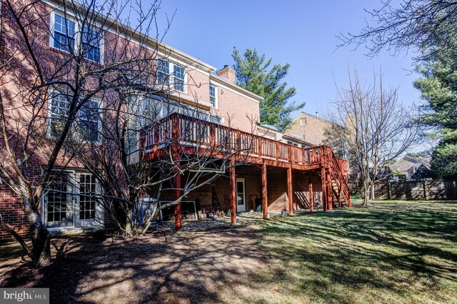 rear view of house featuring a lawn, stairs, a wooden deck, brick siding, and a chimney