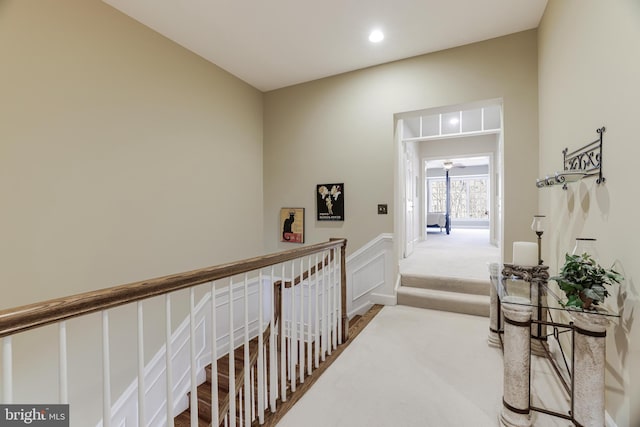 corridor with recessed lighting, a wainscoted wall, a decorative wall, carpet flooring, and an upstairs landing