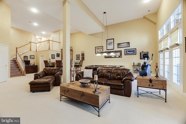 carpeted living area with stairway, a towering ceiling, and recessed lighting