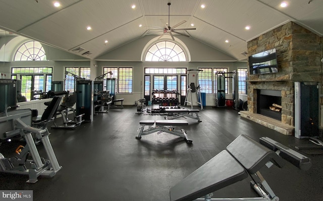 gym with plenty of natural light, visible vents, high vaulted ceiling, and a stone fireplace