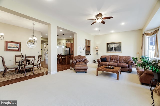 carpeted living area with recessed lighting, baseboards, and ceiling fan with notable chandelier