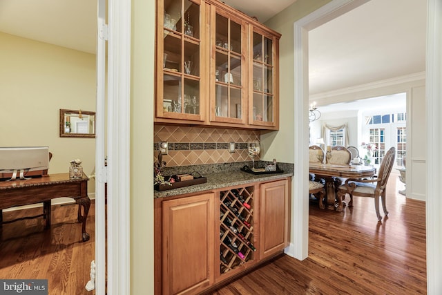 bar featuring a sink, crown molding, dark wood finished floors, and backsplash