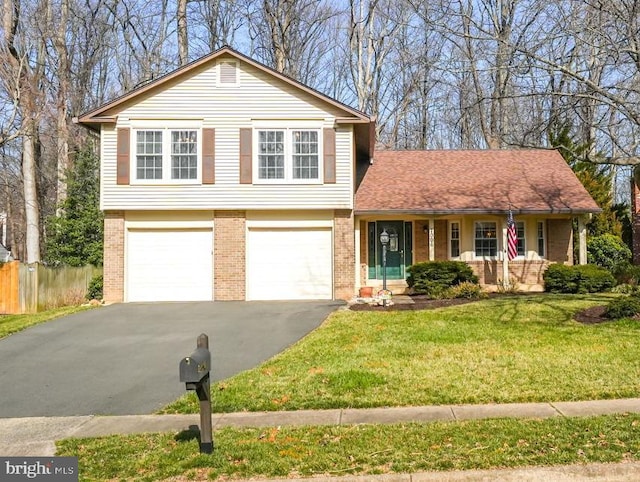 tri-level home with aphalt driveway, fence, covered porch, a front yard, and brick siding