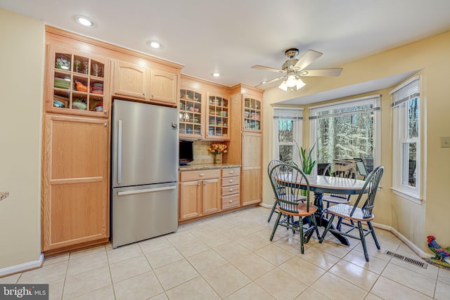 kitchen featuring glass insert cabinets, visible vents, freestanding refrigerator, and light tile patterned floors