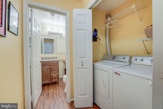 laundry area featuring washing machine and clothes dryer, laundry area, light wood-type flooring, and a sink