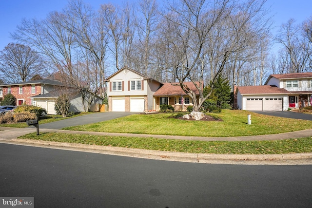 split level home featuring aphalt driveway, a garage, brick siding, and a front lawn