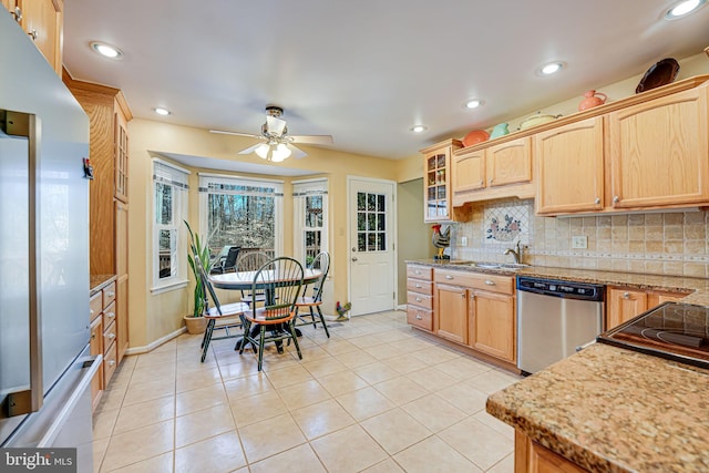 kitchen with tasteful backsplash, light brown cabinets, dishwasher, light stone counters, and light tile patterned flooring